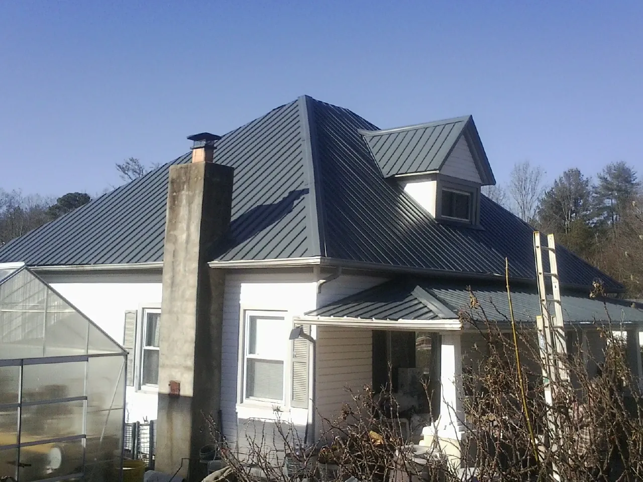 Dark blue standing seam metal roof on a white farmhouse with dormer — Slate & Tile Roof Repair by Roofing Brothers in Ellabell