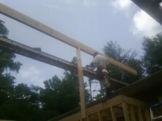 Carpenter setting a ridge beam over a new addition frame — Ice Dam Removal by Roofing Brothers in Ellabell