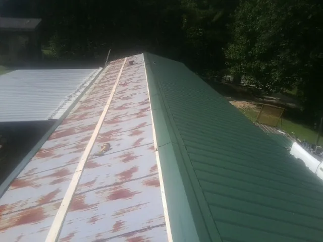Old rusted panels beside newly installed green metal roofing — Wind Damage Roof Repair by Roofing Brothers in Ellabell