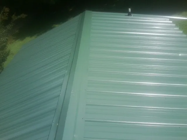New green metal panels meeting at the ridge of a roof — Flat Roof Repair work by our crew in Ellabell