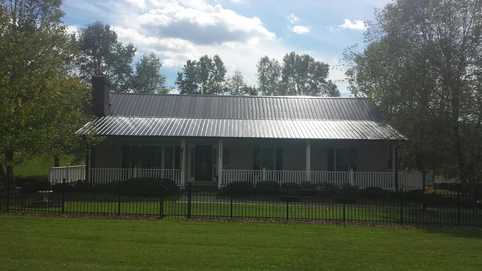 Gray metal roof on a brick ranch with a full width front porch — Gutter Guard Installation work by our crew in Ellabell