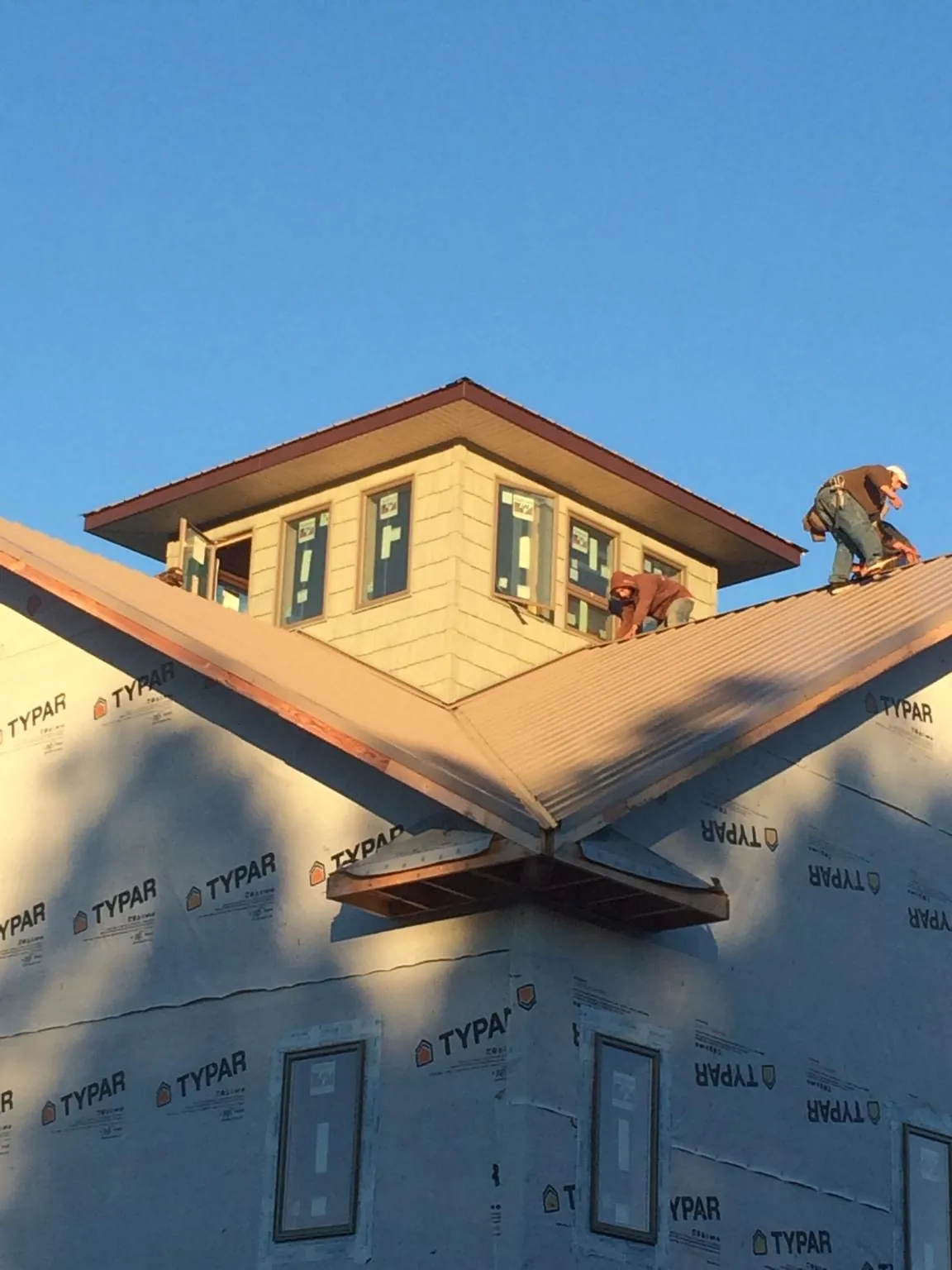 Roofers working around a rooftop cupola on a new metal roof at sunset — Roof Waterproofing in Ellabell by Roofing Brothers